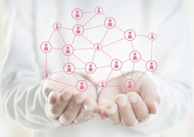 手の上に人のつながりを示すネットワーク図が浮かぶイメージ写真